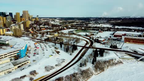Aerial-panaramic-curvy-wide-flyover-winter-partially-icy-North-Saskatchewan-River-headed-East-North-downtown-snow-covered-city-skyscrapper-view-blue-sky-some-clouds-around-modern-Walter-Dale-bridge3-3