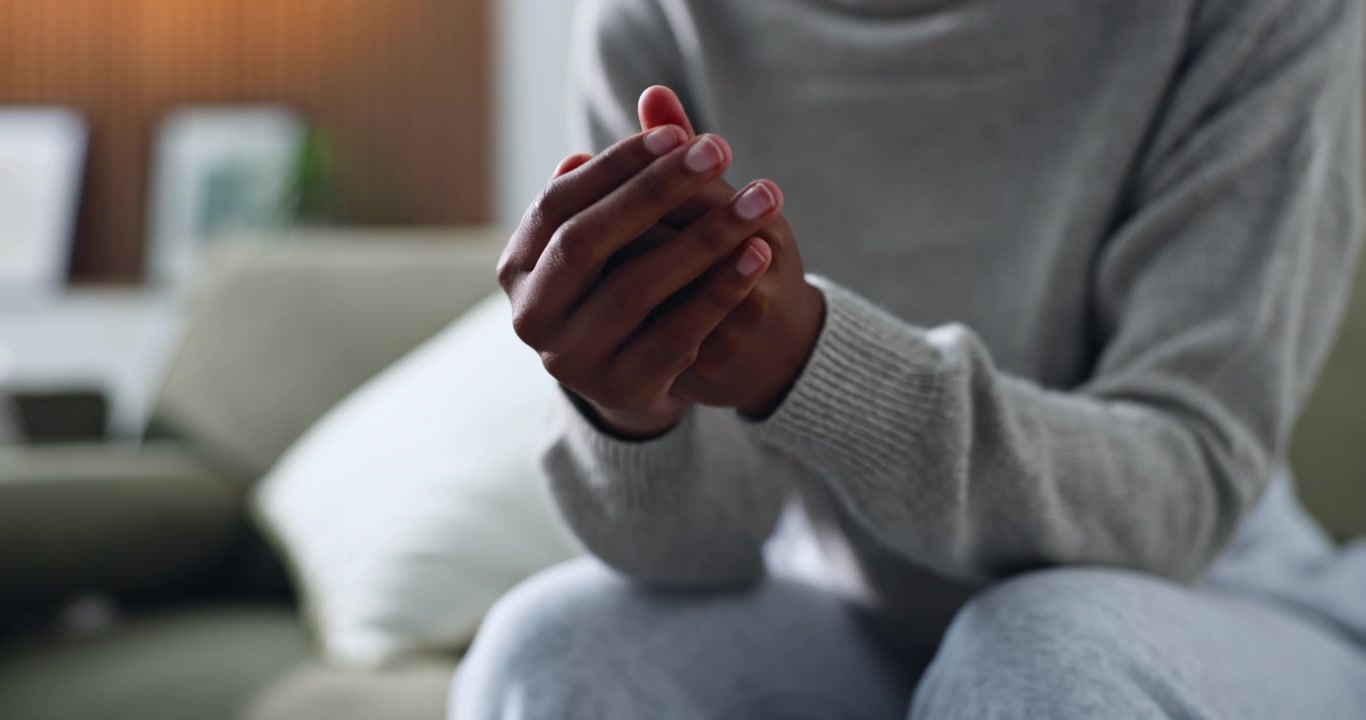 Persona seduta sul divano con le mani giunte
