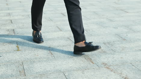 man in business suit walking on a stone pavement