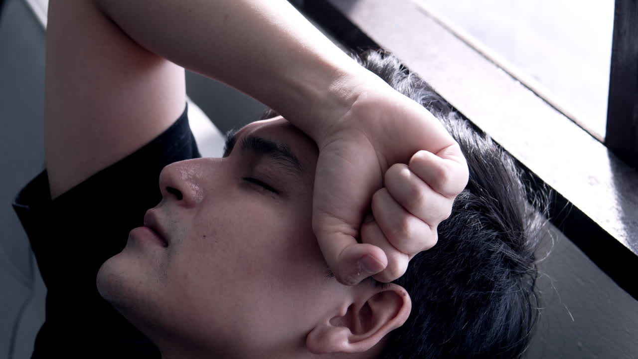An asian man looks restless thinking about a problem while leaning on a chair. Sad mood, depression and disappointment.