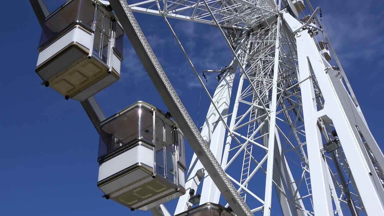 4K. The cabins of a ferris wheel stop and start spinning. Amusement park