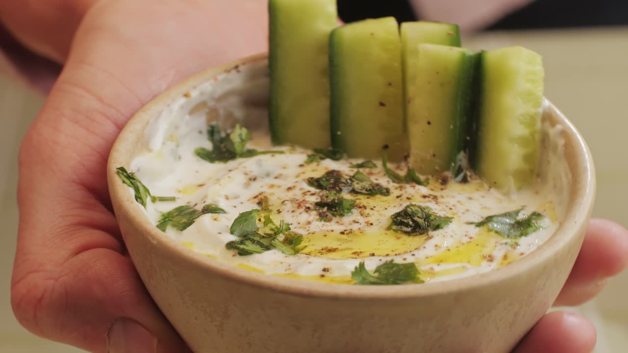 Greek Tzatziki sauce of salted strained yogurt or diluted yogurt mixed with cucumbers and mint, garlic, salt, olive oil on top. High quality 4k footage