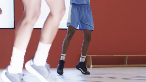 diverse male basketball players dribbling ball and shooting during game at indoor court, slow motion