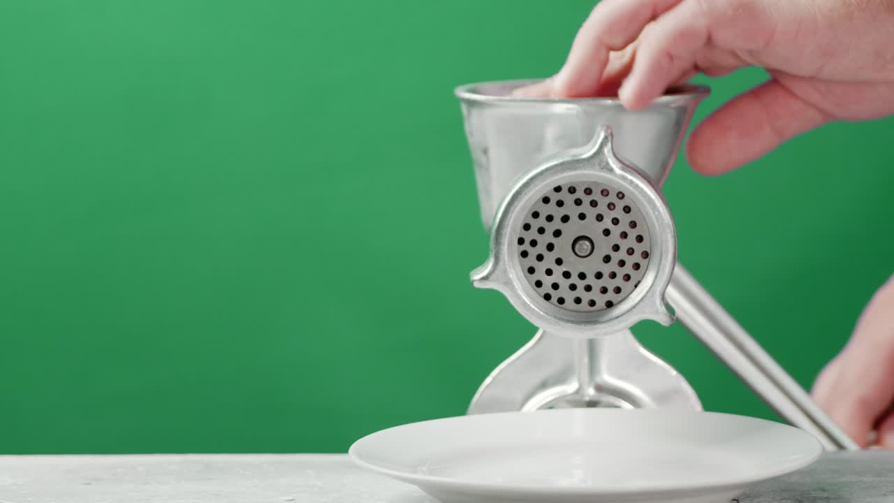 남자의 손은 고기 밀기에서 생 고기를 만니다.