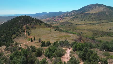 red rocks morrison golden colorado aerial drone follow dinosaur ridge dakota ridge trail mountain biking downhill sport fitness denver foothills front range adult male biker sunny day forward pan up