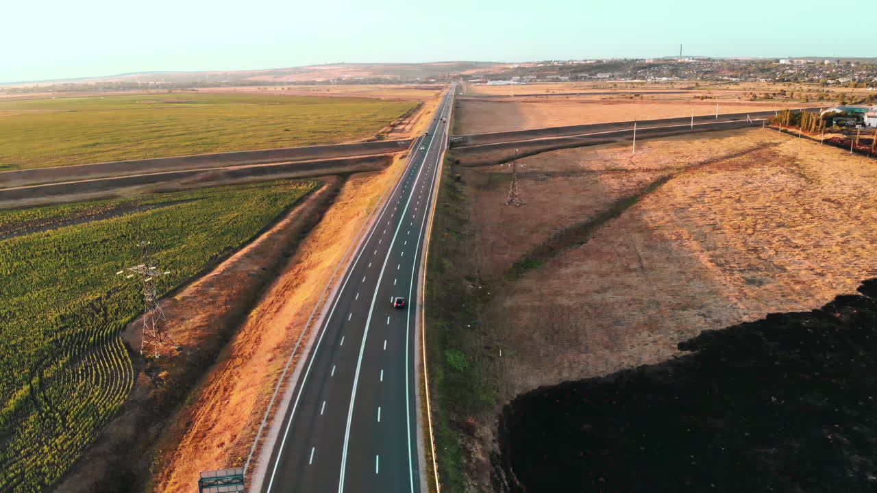 Aerial drone view of a road with moving car in highland. Green fields and hills from north part of Moldova