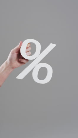 vertical video of hand of caucasian woman holding percent sign with copy space on grey background