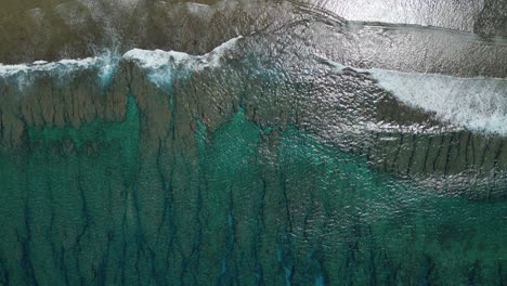 Waves-rolling-in-along-a-tropical-beach---straight-down-aerial-perspective