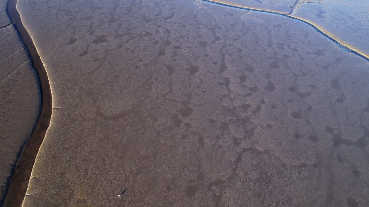 Aerial bird's eye view over lake water drying up and land bridges visible on a brigh