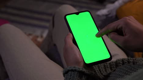 man swiping on mobile phone green screen at home