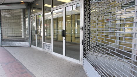 a closed storefront with glass doors, metal security gate, and graffiti in market east, philadelphia.