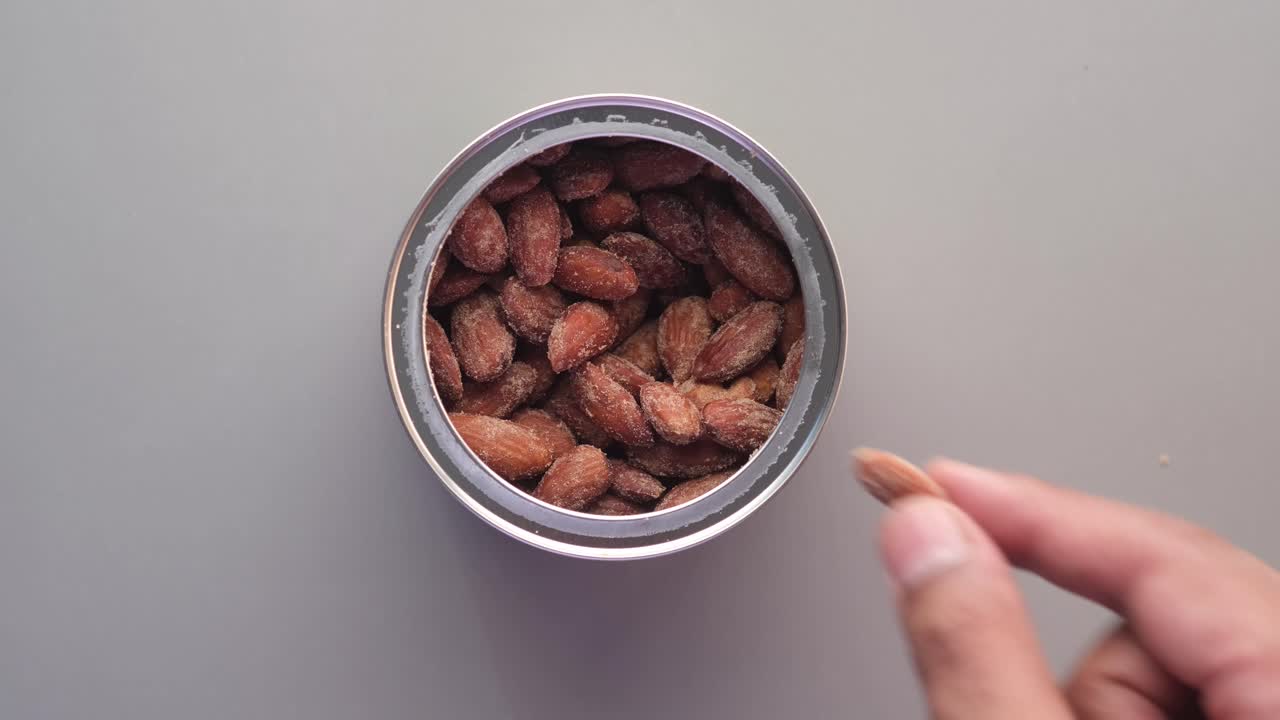 mano alcanzando una lata de almendras asadas
