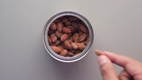mano alcanzando una lata de almendras asadas