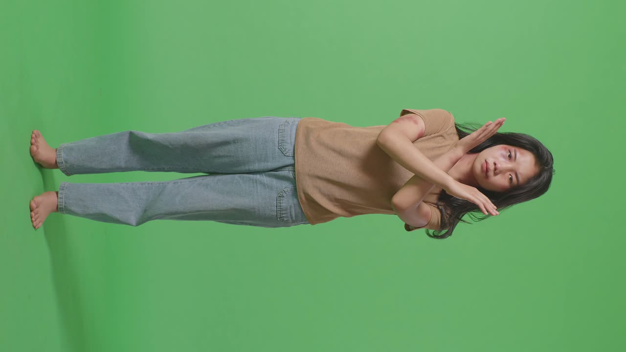 몸에 이 있는 젊은 아시아 여성의 몸이 카메라를 바라보고 녹색 스크린 배경 스튜디오에서 폭력을 멈추기 위해 손을 는 것을 보여줍니다.