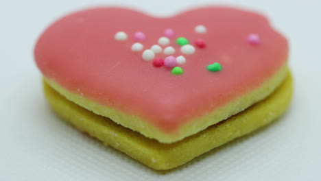 zoom in close-up macro view of the center of a christmas candy in the form of a pink heart decorated with colorful balls and its corpus in close up shot in slow motion capture