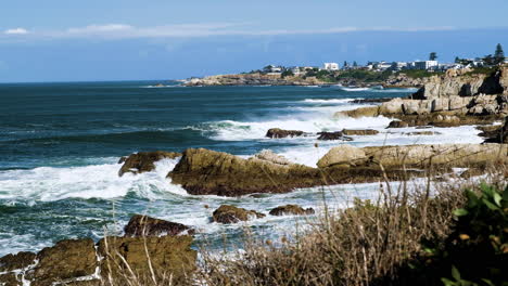 las olas del océano atlántico chocan contra la escarpada costa de hermanus, estática