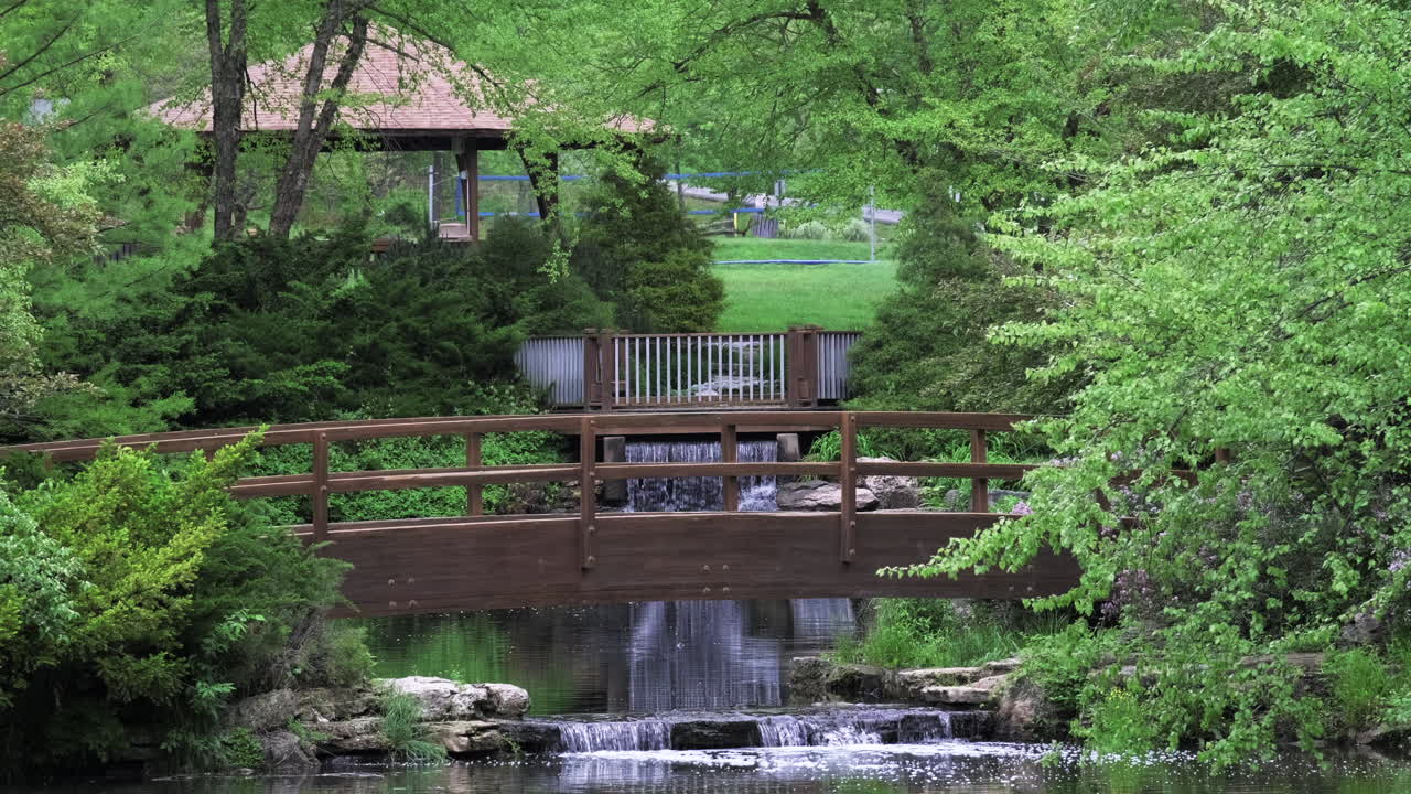 작은 개울, 폭포, 인도교가 있는 도시 공원의 평화로운 장면