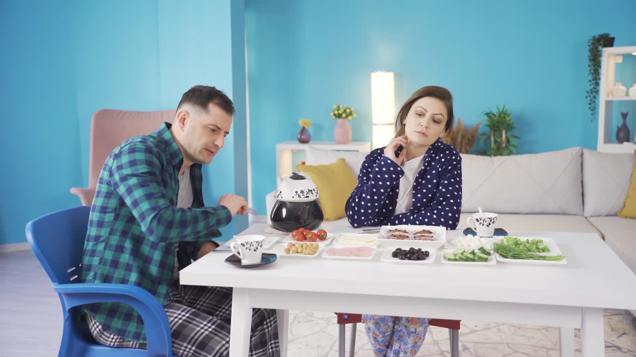 불행한 남편과 아내는 집에서 아침 식사를 하는 동안 싸우고 목소리를 높입니다. 심각한 불일치.