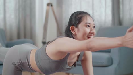 스포츠 옷을 입은 젊은 아시아 운동선수 여성이 집에서 매트 위에 균형 잡는 테이블 포즈에서 요가를 하는 근접 초상화
