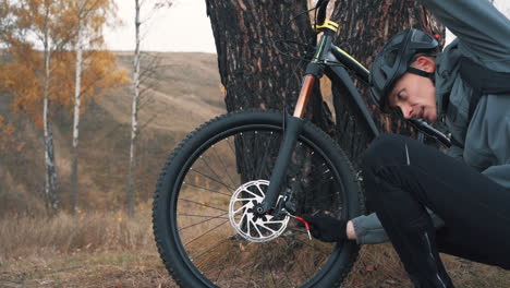 athlete man fixing a mountain bike in the countryside