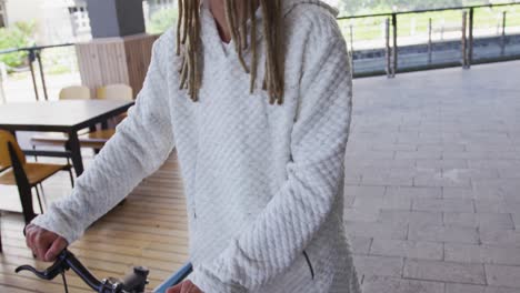 mixed race man with dreadlocks wheeling a bicycle in the street