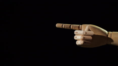 wooden hand points with finger on black background