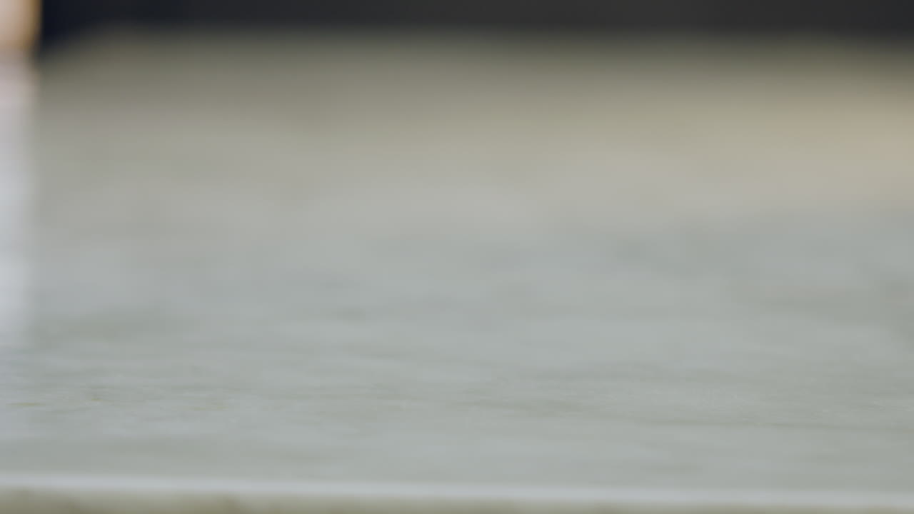 Close-up of a chef's hands placing a green apple, a peeler, and a knife next to a white chopping board on a white countertop