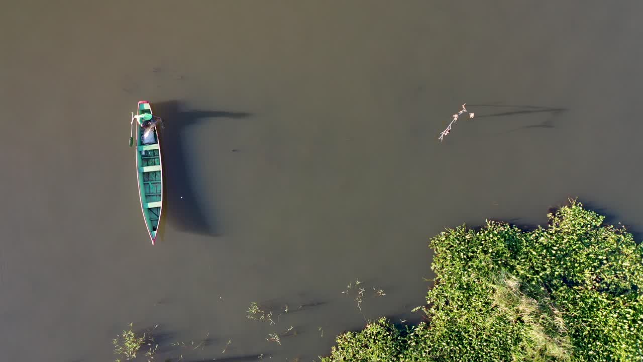 vista aérea de pescador con canoa tirando red de pesca en el río
