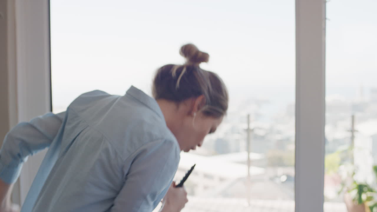 행복한 젊은 여성이 집에서 노래하고 즐겁게 성공적인 라이프 스타일을 축하하고 춤을 추고 카라오케 음악 엔터테인먼트를 즐기고 있습니다.