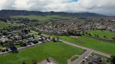 a stunning aerial view of murrieta, california, showcasing vast green spaces, open landscapes, picturesque mountain views, and scattered suburban homes, creating a serene and scenic setting