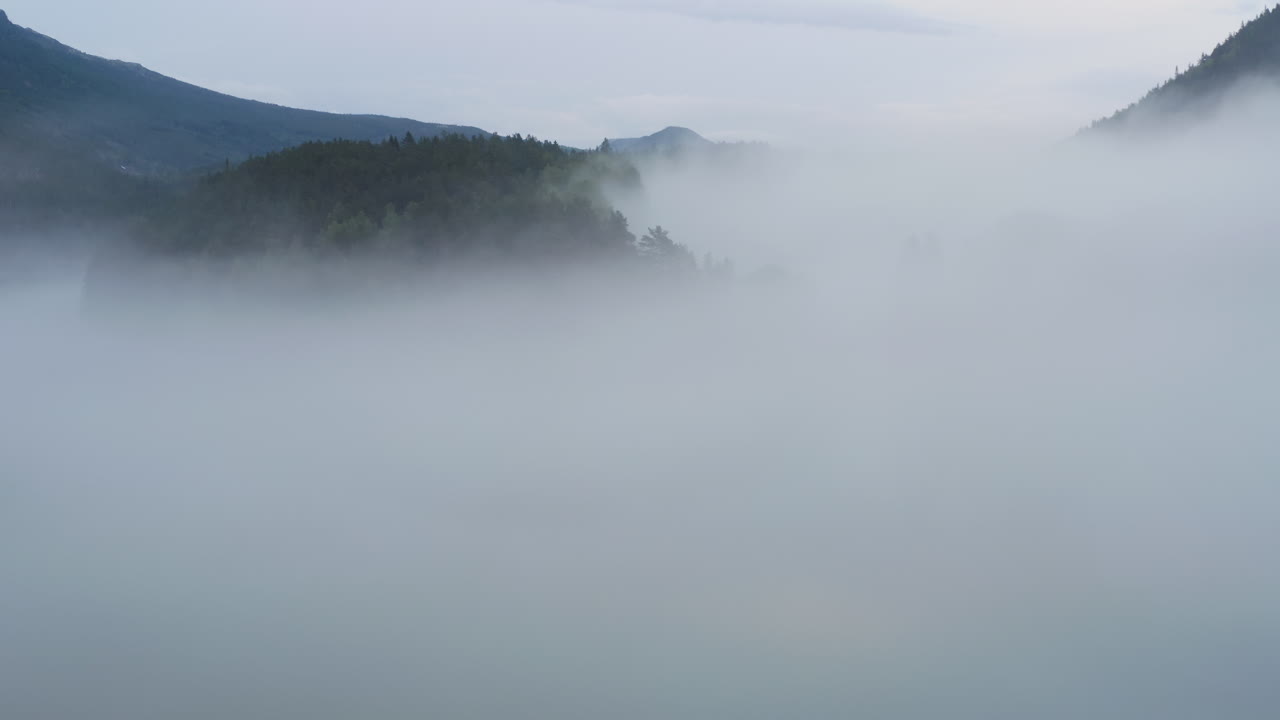 Flight over a foggy river. The mist is hanging low over the landscape creating a dark mystical mood over the whole scene.