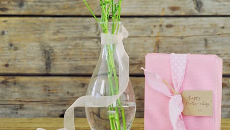 Gift-box-and-flower-vase-on-wooden-surface