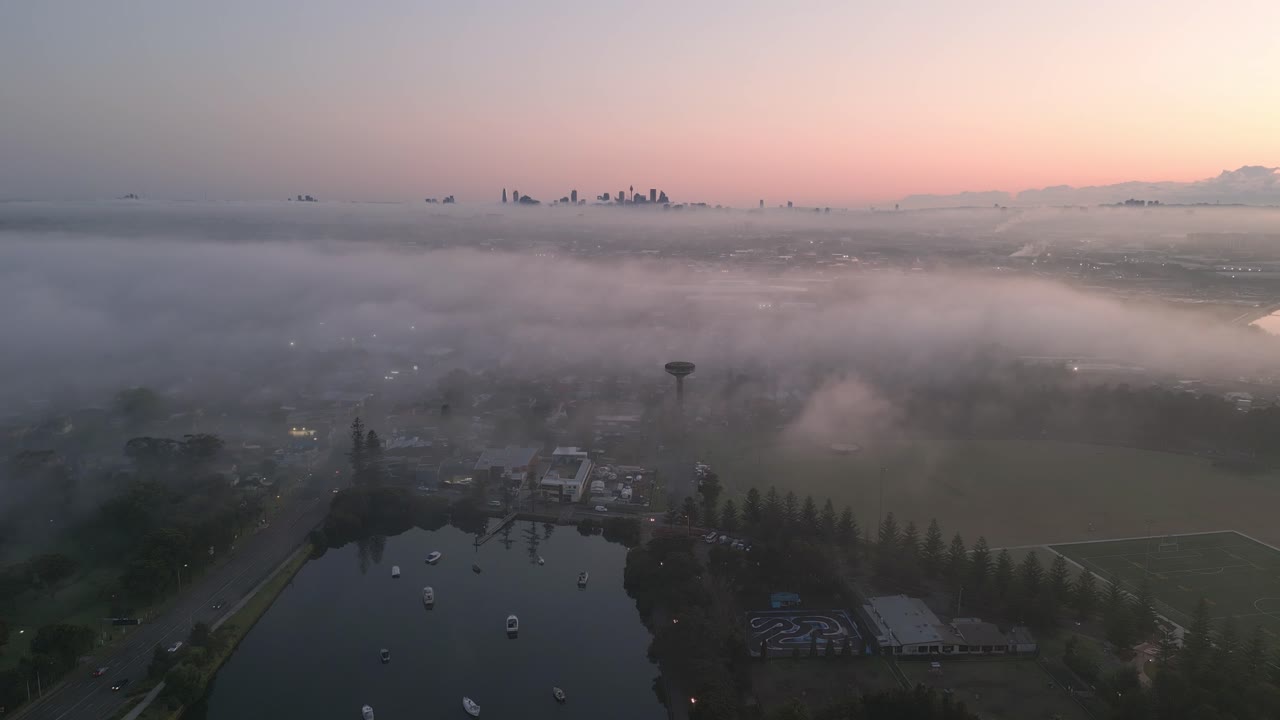 지평선에서 도시 전망을 감상할 수 있는 안개 낀 시드니 교외의 공중 비디오, 일출 시 호주