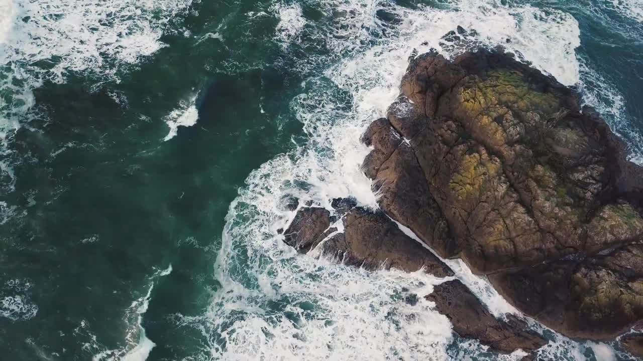 Vista aerea di onde oceaniche che si infrangono contro la costa rocciosa, mostrando il potente movimento del mare e la bellezza naturale costiera. Ideale per video di viaggio, progetti cinematografici, temi marini e natura panoramica