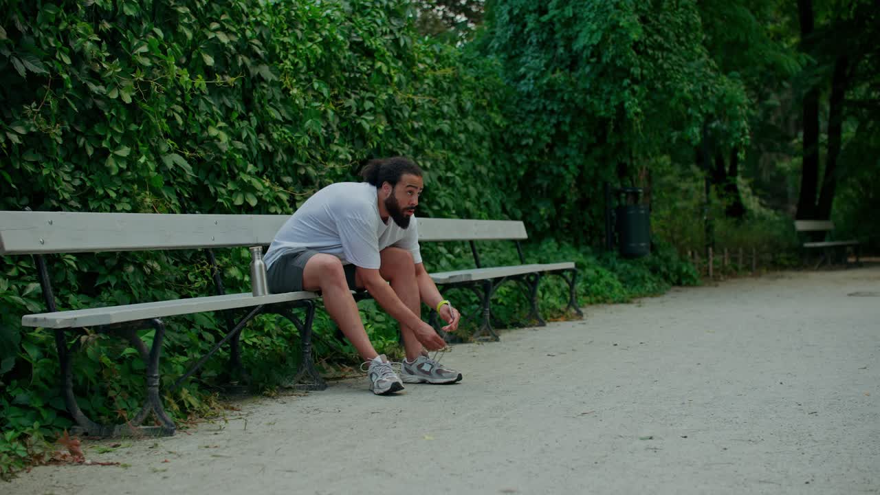 公園のベンチで靴ひもを結ぶ男性