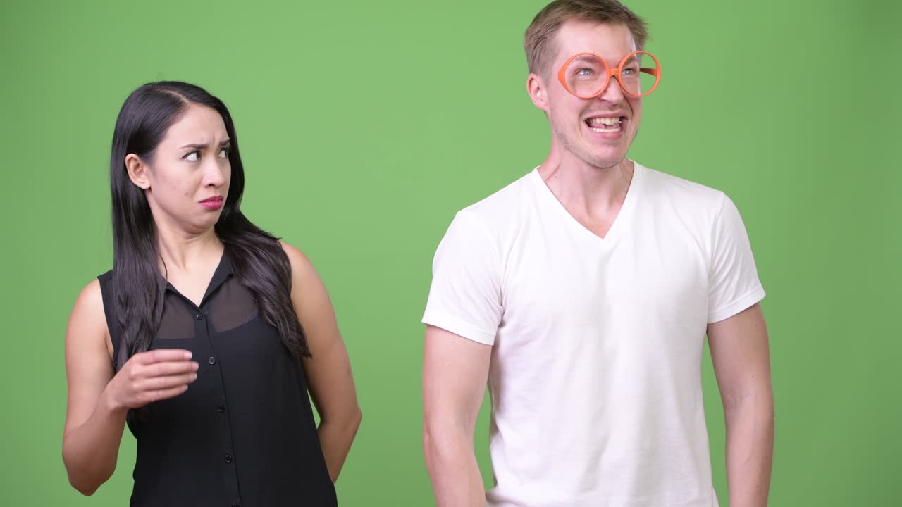 Young nerd man farting beside young Asian businesswoman