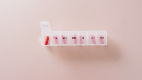 video de pastillas rojas en la caja de pastillas semanal en fondo rosa con espacio para copiar.