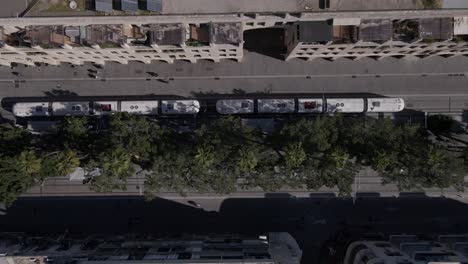 tram driving on rails through city streets, overhead aerial view