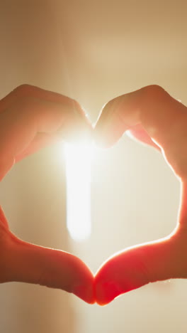 de manos formando una forma de corazón contra los brillantes rayos del sol del hogar, creando una silueta cálida y amorosa