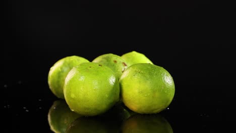 limes rotating on a glossy black background
