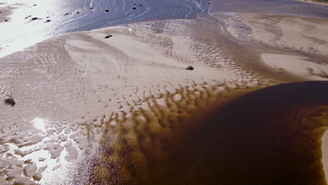 Aéreo:-Patrones-De-Arena-únicos-En-La-Desembocadura-Del-Río-Bot,-Aguas-Marrones-De-La-Laguna-Ricas-En-Tanino