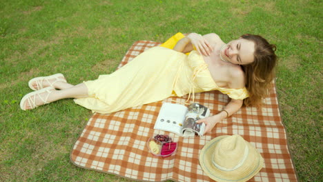 beautiful woman lying on side looking up at camera while on picnic, reading