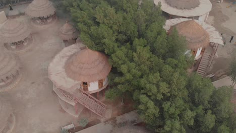 Vista-Aérea-Sobre-Edificios-De-Vacaciones-Con-Techo-De-Paja-En-El-Refugio-De-Vida-Silvestre-Mehrano-En-Kotdiji