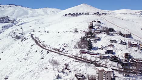 órbita aérea establecimiento de farellones nevados con estaciones de esquí el colorado y la parva en un día soleado al fondo, chile