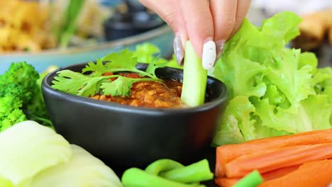 hands assembling a salad with various fresh ingredients