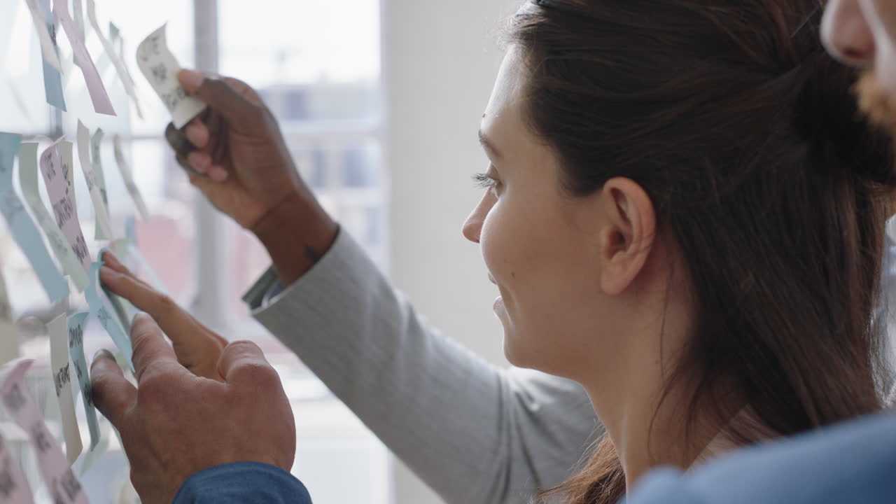 joven mujer de negocios usando notas adhesivas haciendo una lluvia de ideas para resolver problemas con diversos colegas compartiendo ideas creativas para la solución en una reunión de oficina