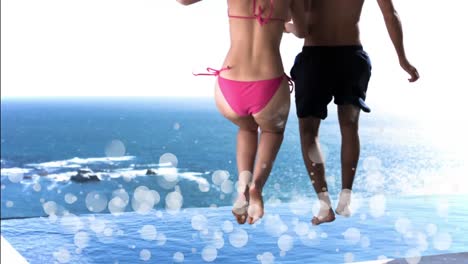 Young-couple-jumping-into-a-swimming-pool-surrounded-by-white-bubbles