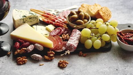 Cold-snacks-board-with-meats--grapes--wine--various-kinds-of-cheese