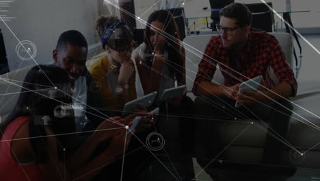 coworkers collaborating in office lounge, viewing technology data graphics over tablets and phone