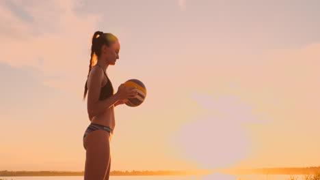 chica atlética jugando voleibol de playa salta en el aire y golpea la pelota sobre la red en una hermosa noche de verano. mujer caucásica anota un punto.